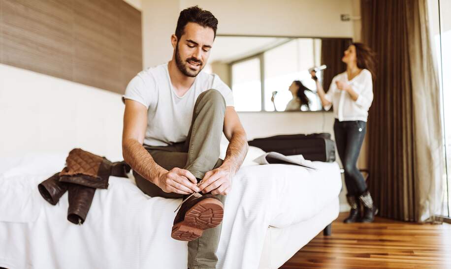 Paar im Hotel Zimmer mach sich fertig um auszugehen | © Gettyimages.com/franckreporter