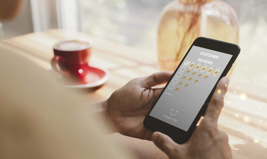 Frauen Hand halten Smartphone wählen Sie das 5-Sterne-Symbol, um Zufriedenheit im Service zu geben | © Gettyimages.com/aogreatkim