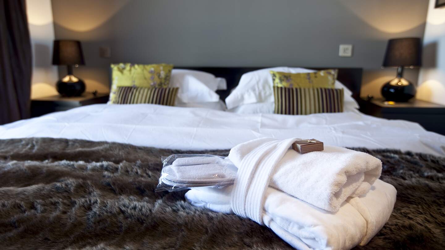 Modernes Hotelzimmer mit Kingsize-Bett, auf dem Handtuecher liegen | © Gettyimages.com/WILLSIE