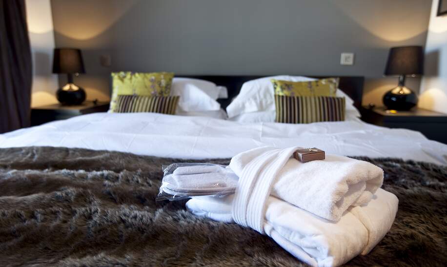 Modernes Hotelzimmer mit Kingsize-Bett, auf dem Handtuecher liegen | © Gettyimages.com/WILLSIE