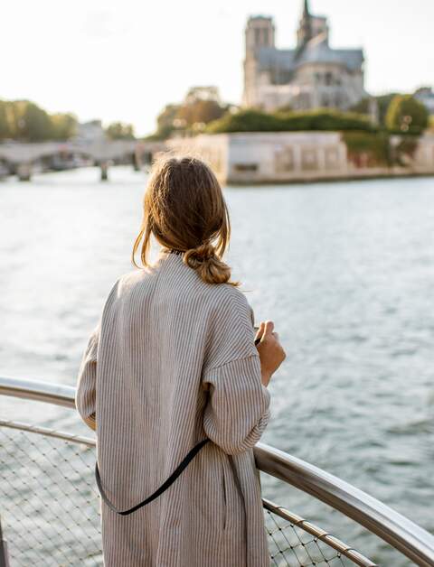 Frau genießt den Landschaftsblick auf die Stadt Paris vom Boot aus | © Gettyimages.com/RossHelen