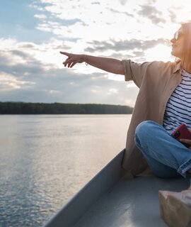 Eine Frau zeigt von einem Boot in die Breitengrade | © Gettyimages.com/Olezzo