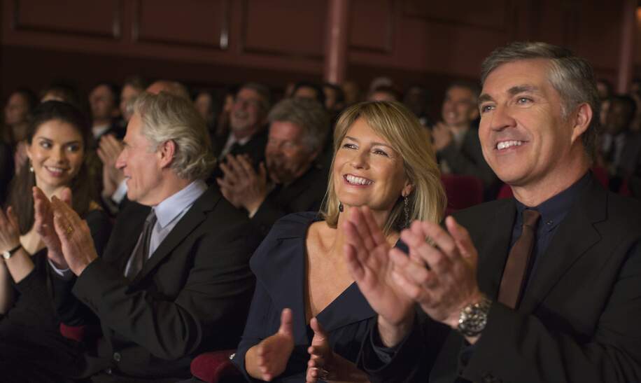 Das Publikum vom Theater klatscht in die Haende und laechelt | © Gettyimages.com/Caiaimage/Samedwards