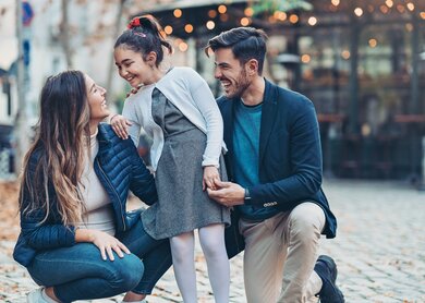 Familie, bestehend aus Mutter, Tochter und Vater lächeln während sie sich anschauen | © Gettyimages.com/pixelfit