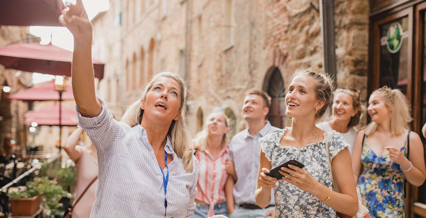 Kleine Reisegruppe auf historischem Stadtrundgang. Sie hoert einem Reiseleiter zu, der ueber die Architektur und die Geschichte spricht. | © Gettyimages.com/SolStock