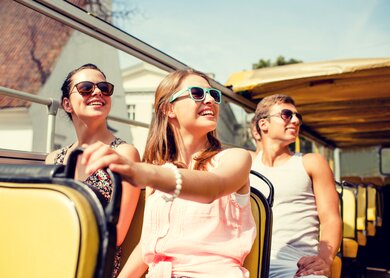 Gruppe von laechelnden Freunden, die mit dem Tourbus reisen | © Gettyimages.com/dolgachov