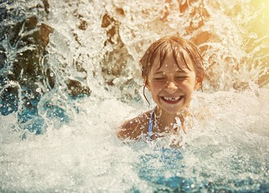 Kleines Maedchen spielt im Wasserfall im Wasserpark  | © Gettyimages.com/Imgorthand
