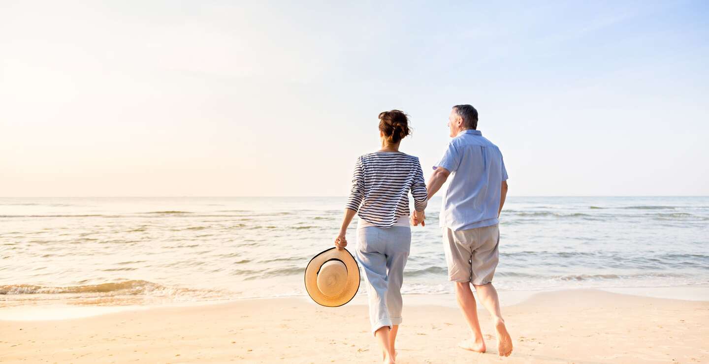 Aktives Seniorenpaar, das am Strand spazieren geht | © Gettyimages.com/FredFroese