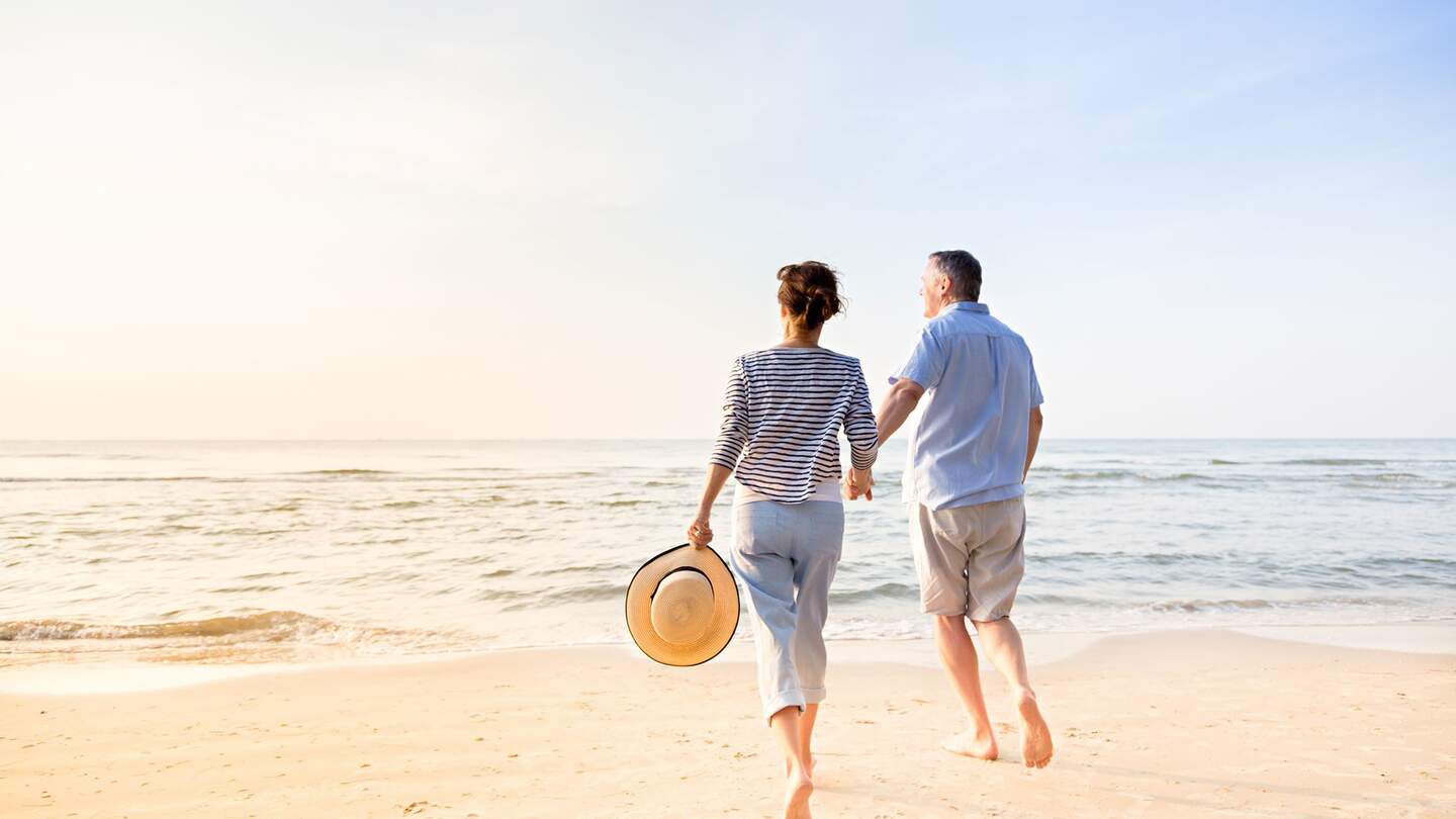 Aktives Seniorenpaar, das am Strand spazieren geht | © Gettyimages.com/FredFroese