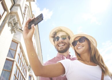 Glückliches Mädchen, das Selfie mit ihrem Freund in der Nähe macht | © Gettyimages.com/shironosov