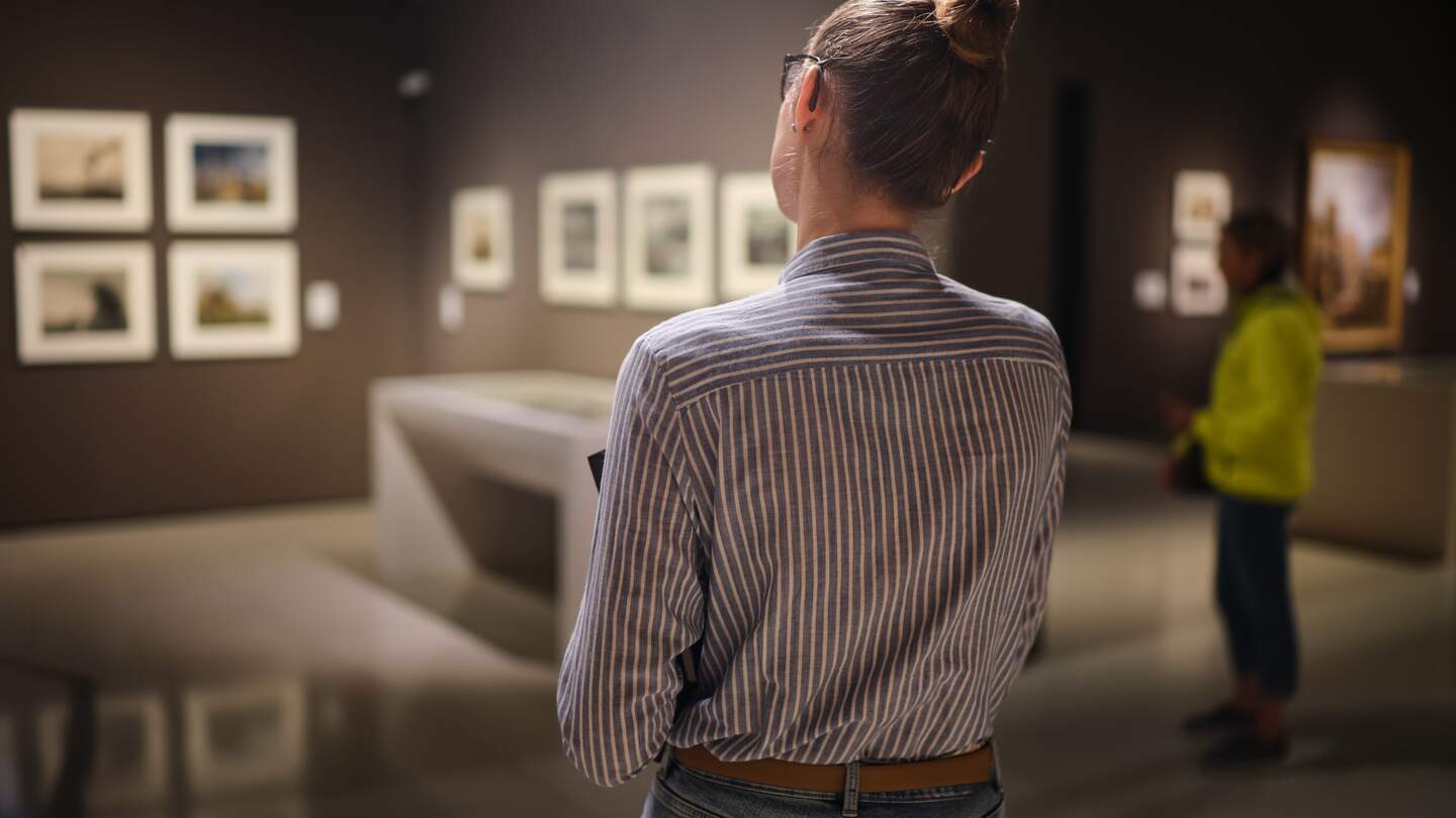 Frau steht mit dem Rücken zur Kamera in einem Museum | © Gettyimages.com/jenoche