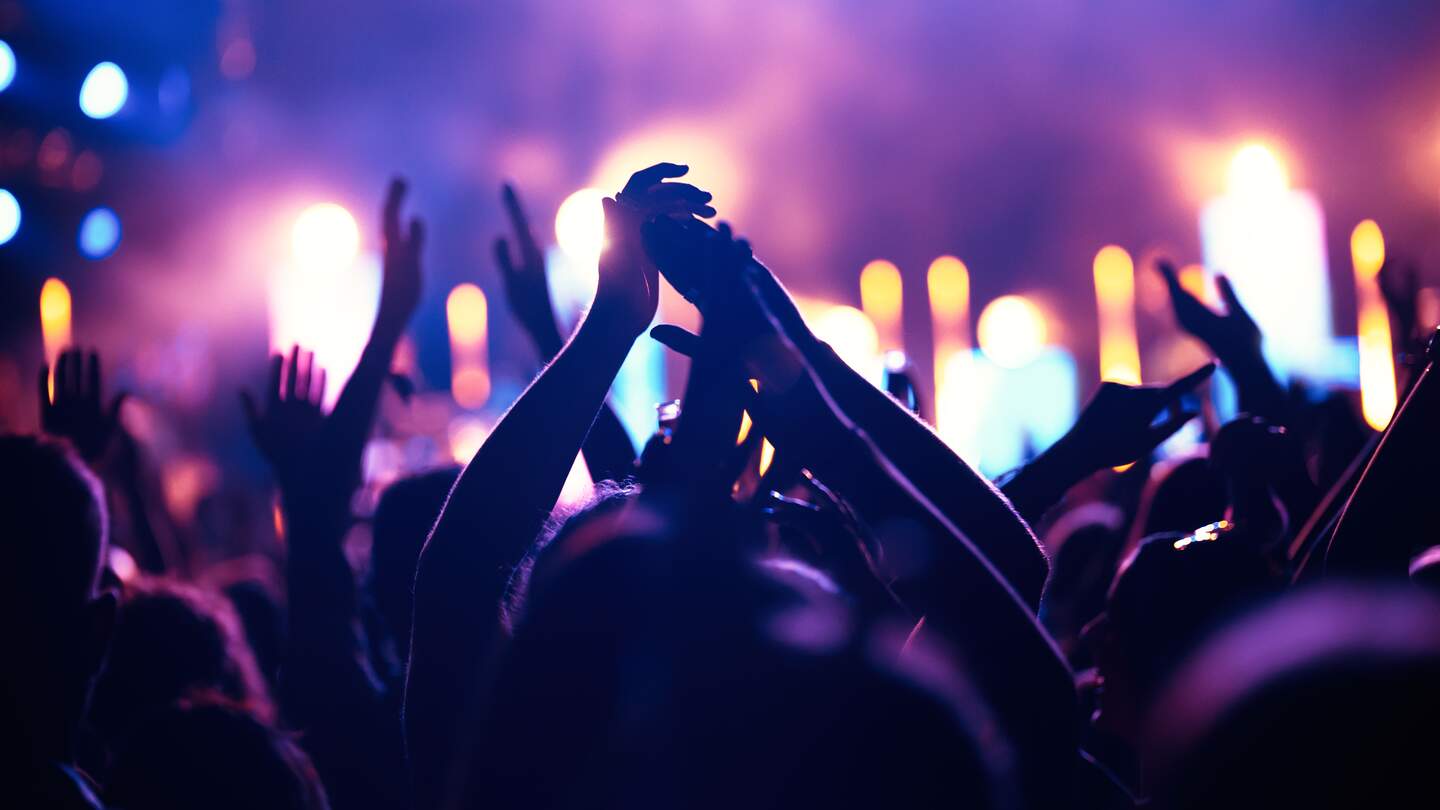 Publikum hat die Hände in der Luft bei einem Konzert | © Gettyimages.com/ANDOR BUJDOSO