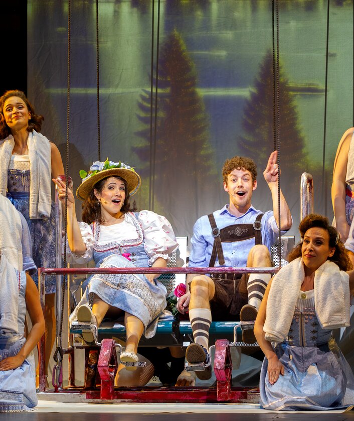 Szenenbild mit Celina dos Santos als Monika, Mathias Reiser als Freddy und Ensemble von KU’DAMM 59 - Berlins Hit-Musical geht weiter! | © sunstroem