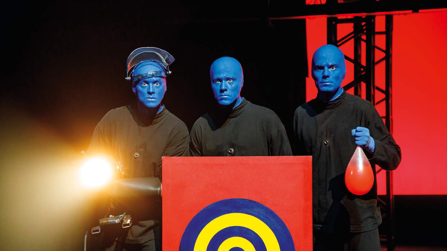 Blue Man Group hinter einer Zielscheibe, einer haelt einen Ballon in der Hand | © Stage Entertainment/Morris Mac Matzen