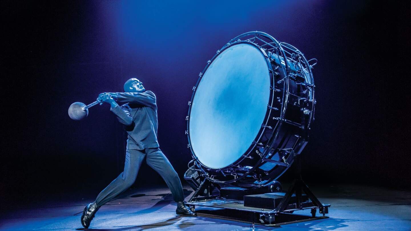 Einer der Kuenstler schlaegt auf eine riesige Trommel | © Stage Entertainment