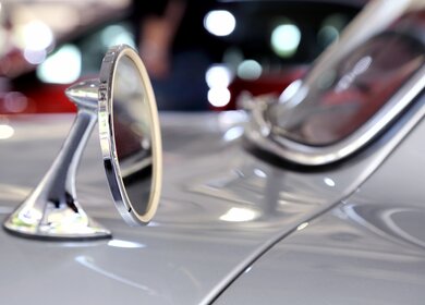 Nahaufnahme eines Spiegels eines silberfarbenen Mercedes-Benz 300  | ©  Gettyimages.com/vuk8691