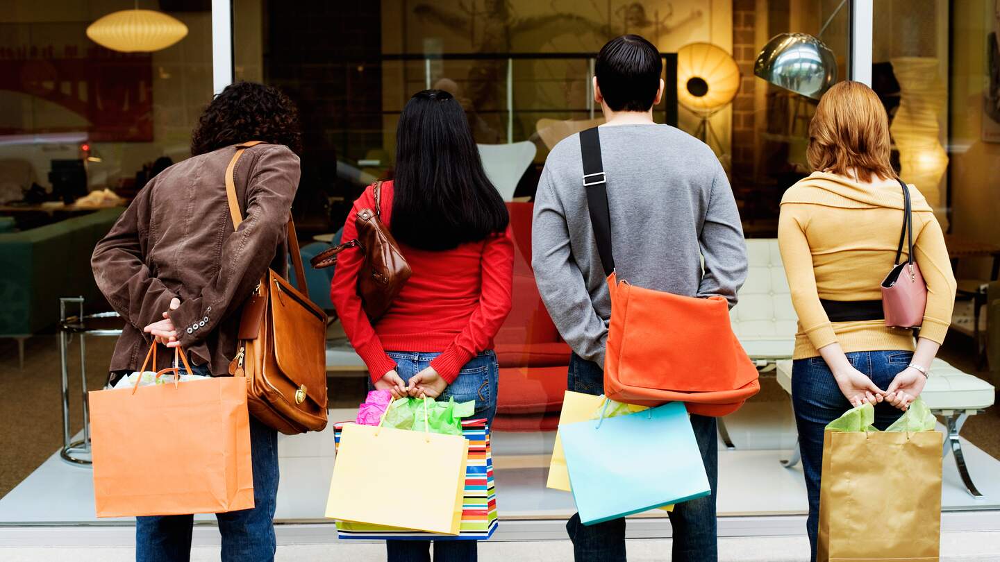 Rückansicht von Menschen beim Schaufensterbummel mit bunten Einkaufstaschen | © Gettyimages.com/Jupiterimages