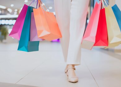 Frau traegt bunte Einkaufstueten und kaeuft durch ein Einkaufszentrum.  | © Gettyimages.com/PonyWang