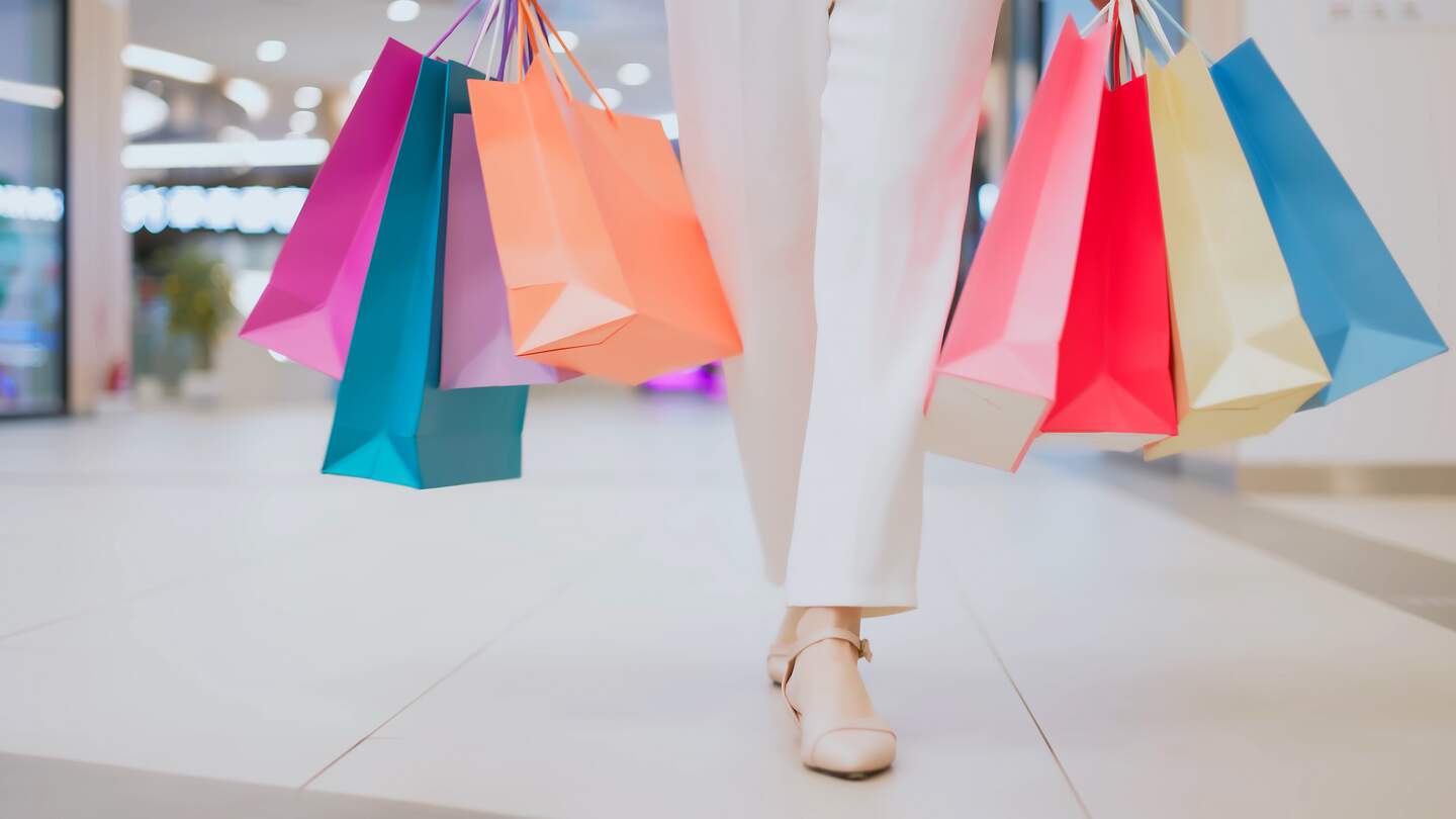 Frau traegt bunte Einkaufstueten und kaeuft durch ein Einkaufszentrum.  | © Gettyimages.com/PonyWang