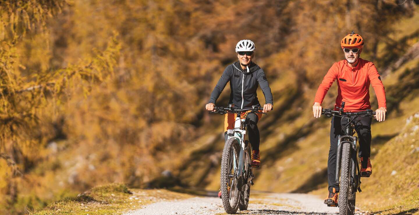Paar auf einer Radtour auf einem Berg mit herbstlich gefärbte ländliche Landschaft. | © Gettyimages.com/amriphoto