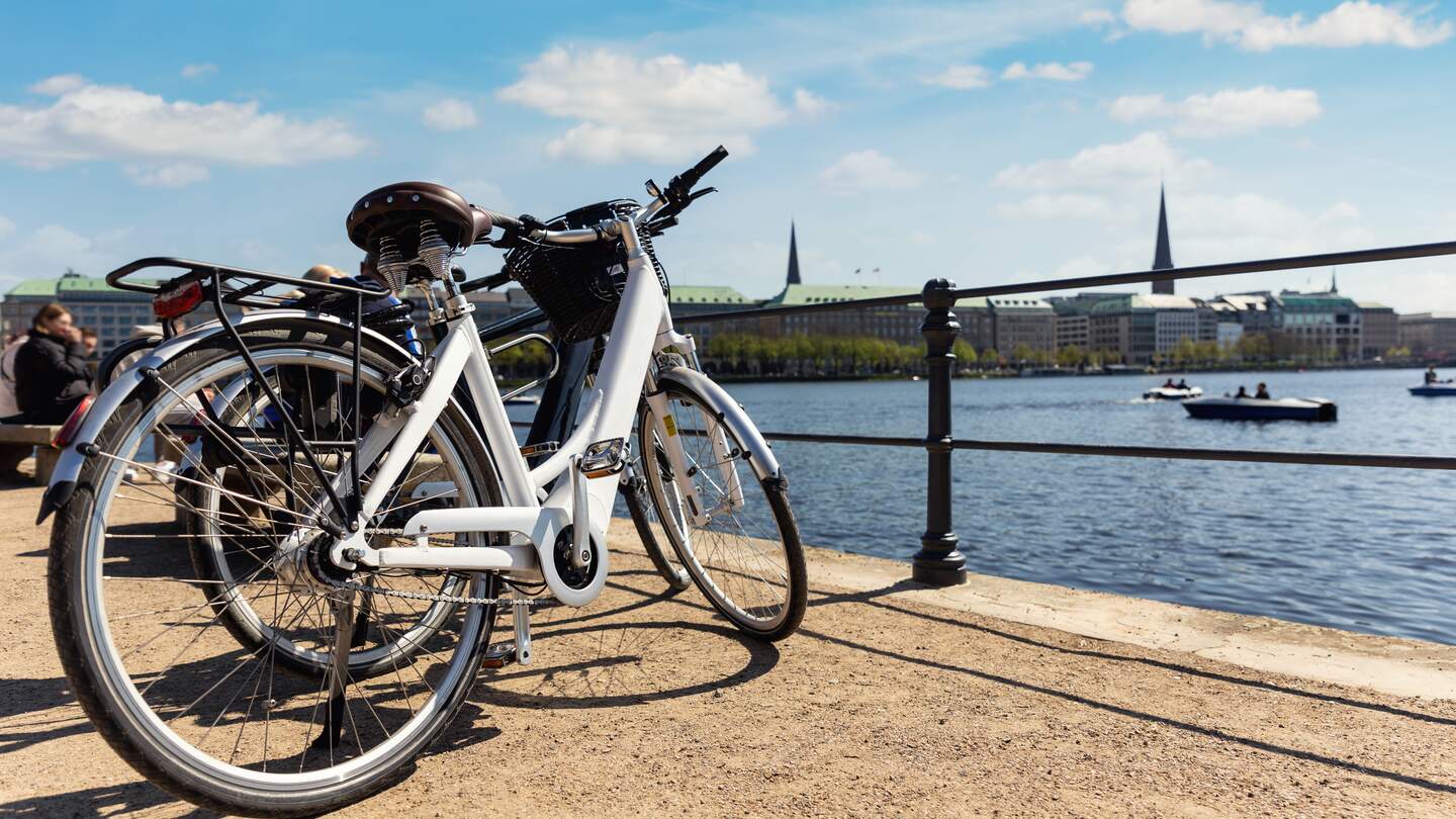 Malerische Aussicht, zwei moderne Fahrräder, die am Ufer der Alster in der Hamburger Straße geparkt sind, Altstadt, Hintergrund, Sommertag, Panoramablick | © gettyimages.com/GKV