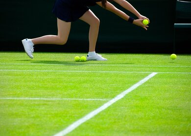 ein Ballmaedchen, die Tennisbaelle wahrend eines Spiels einsammelt | ©  2016 Thinkstock.