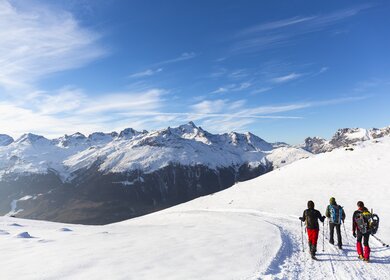 Wanderer wandern auf schneebedeckter Strasse im Hochgebirge | © Gettyimages.com/deimagine