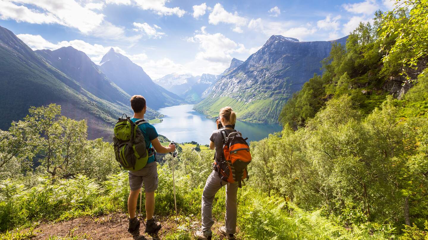 Zwei Wanderer am Aussichtspunkt in Bergen mit See | © gettyimages.com/NicoELNino