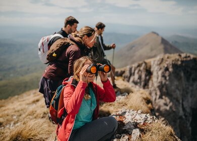 Ein Gruppe von jungen Wanderen hält auf einer Bergkuppe Ausschau | © Gettyimages.com/eclipse_images