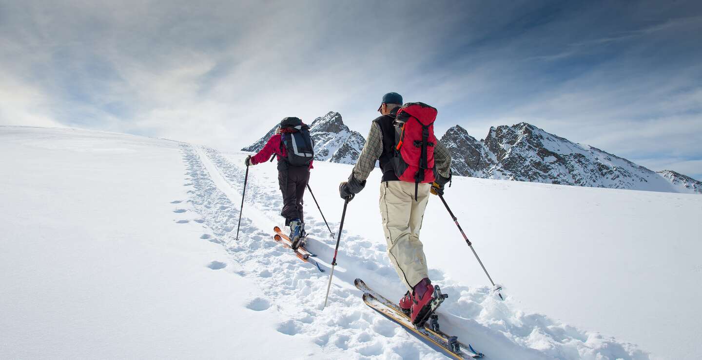 Zwei aeltere Alpinskifahrer steigen auf Skier  | © gettyimages.com/michelangeloop