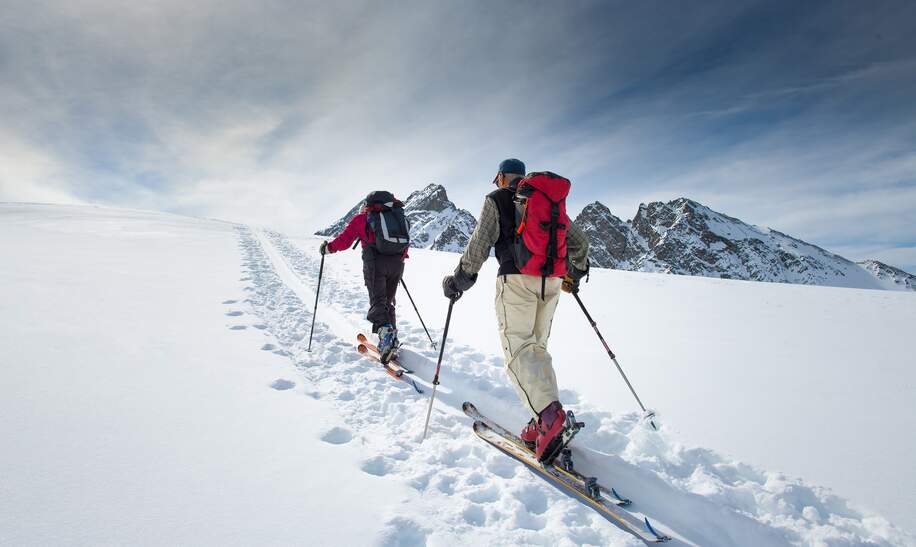 Zwei aeltere Alpinskifahrer steigen auf Skier  | © gettyimages.com/michelangeloop