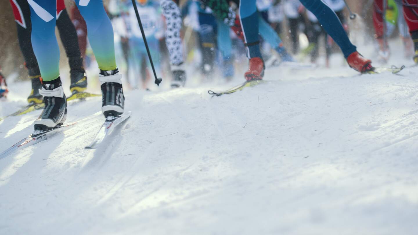 Skimarathon - defokussierte Sicht auf viele Beine von Sportlern, die auf Schnee laufen | © Gettyimages.com/studia72