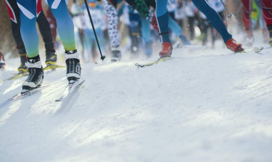 Skimarathon - defokussierte Sicht auf viele Beine von Sportlern, die auf Schnee laufen | © Gettyimages.com/studia72