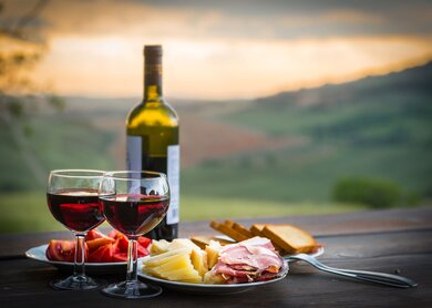 Stillleben Rotwein, Kaese und Schinken vor verschwommenem Hintergrund | © Gettyimages.com/scorpp