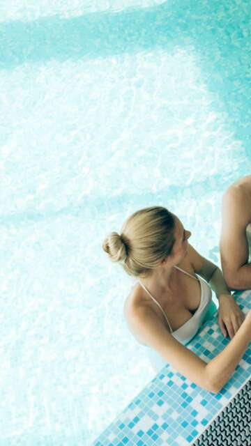 Aufsicht auf ein Paar, dass sich im Pool mit Cocktails entspannt | © Gettyimages.com/nd3000