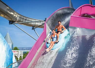 Pärchen auf der Big Wave Rutsche in der Therme Erding auf einem Schwimmreifen