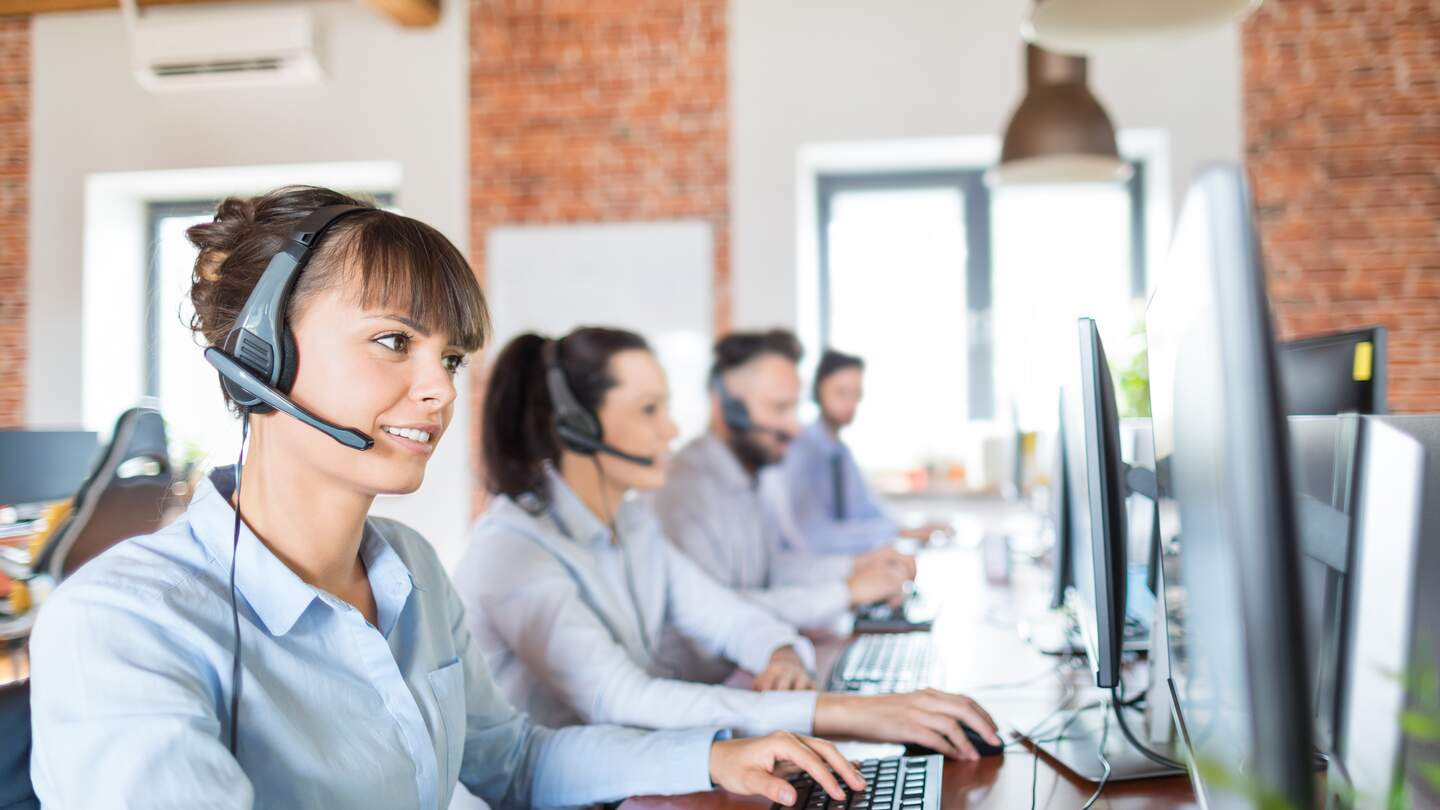 Callcenterarbeitskraft von ihrem Team begleitet | © Gettyimages.com/scyther5