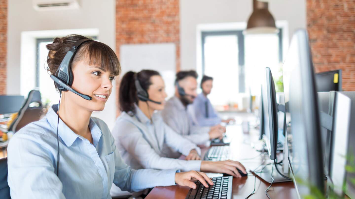 Callcenterarbeitskraft von ihrem Team begleitet | © Gettyimages.com/scyther5