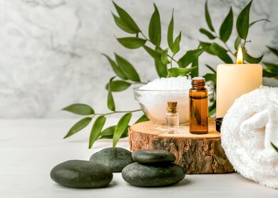 Schönheitsbehandlungen für Spa-Verfahren auf weißem Holztisch. Massagesteine, ätherische Öle und Meersalz | © Gettyimages.com/ronstik