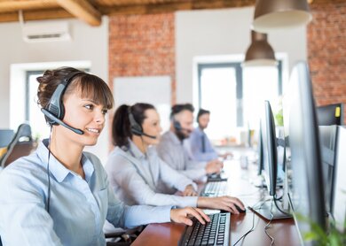 Callcenterarbeitskraft von ihrem Team begleitet | © Gettyimages.com/scyther5