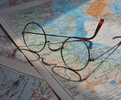 Brille liegt auf mehreren Weltkarten und wirft einen Schatten auf sie | © Pixabay/beasternchen
