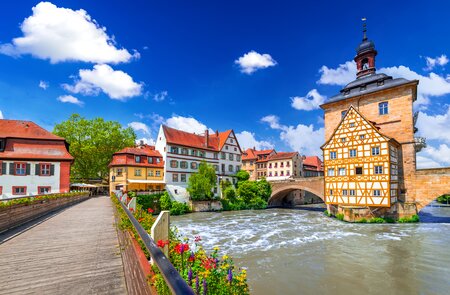 Blick auf das Rathaus und eine mit Blumen geschmückte Brücke in Bamberg | © Gettyimages.com/emicristea