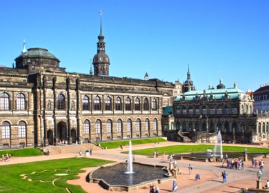 Gartenanlage des Zwinger-Palast in Dresden voller Touristen bei hellblauem Himmel | © Gettyimages.com/Marina79