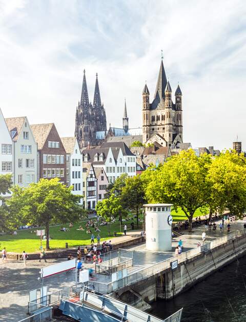 Menschen laufen auf der Rheinpromenade in Köln, der Blick auf die Kölner Altstadt | © Gettyimages.com/querbeet