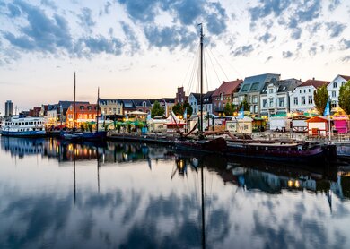 Husumer Hafen bei Sonnenuntergang Nordfriesland Deutschland  | © Gettyimages.com/mlenny Stadtbild des Husumer Hafens in der Daemmerung nach Sonnenuntergang. Voller verschiedener Streetfood-Staende, Bars und Kioske, die für den Start der beruehmten Husumer Hafentage vorbereitet sind. Die Husumer Hafentage sind das groesste oeffentliche Stadtfest an der deutschen Nordseeküste Schleswig-Holsteins. Stadt Husum, Nordfriesland, Schleswig-Holstein, Deutschland. | © Gettyimages.com/mlenny