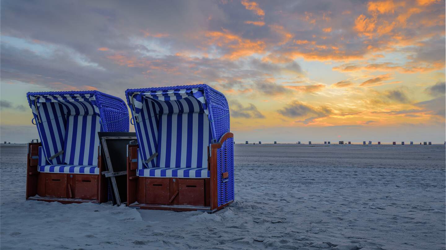 Zwei Strandsessel nebeneinander am weißen Sandstrand mit Sonnenuntergang Dämmerung im Himmel | © Gettyimages.com/frederickdoerschem