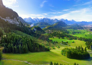 Beruehmtes Schloss Neuschwanstein sehen in der Ferne, liegt auf einem schroffen Huegel über dem Dorf Hohenschwangau im suedwestlichen Bayern | © Gettyimages.com/MNStudio