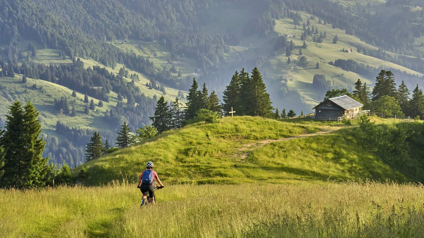 Frau auf Elektro-Mountainbike in den deutschen Alpen | © Gettyimages.com/Uwe Moser Frau faehrt ihr Elektro-Mountainbike in den Bergen oberhalb von Oberstaufen mit Nagelfluh-Bergkette im Hintergrund, Allgaeuer Alpen | © Gettyimages.com/Uwe Moser