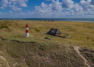 Luftaufnahme eines Leuchtturms auf Sylt | © Gettyimages.com/frederickdoerschem Panorama-Luftaufnahme des Ellenbogens, der Halbinsel an der Nordküste der Insel Sylt, List. Deutschlands noerdlichster Leuchtturm.  | © Gettyimages.com/frederickdoerschem
