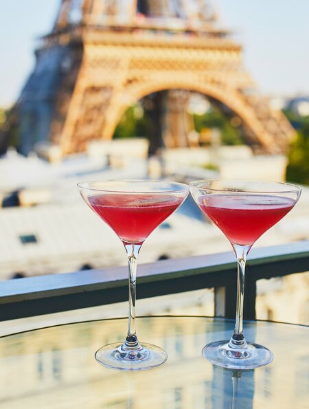Zwei Cosmopolitan-Cocktails in traditionellen Martinigläsern mit Blick auf den Eiffelturm in Paris, | © Gettyimages.com/encrier